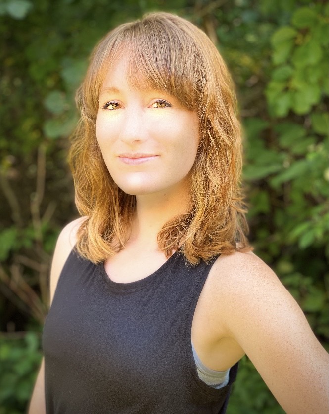 Miss Rachel headshot. Wearing black tank top in front of greenery