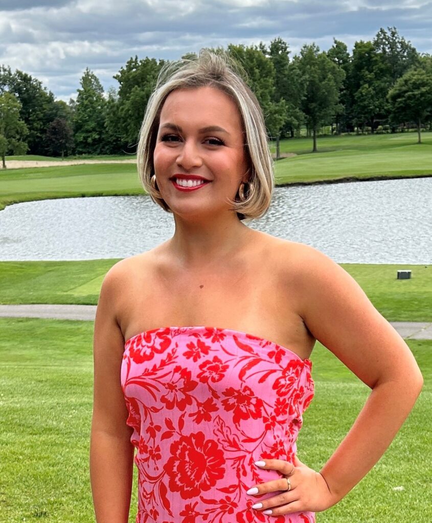 Kristen headshot. Wearing pink and red dress on golf course
